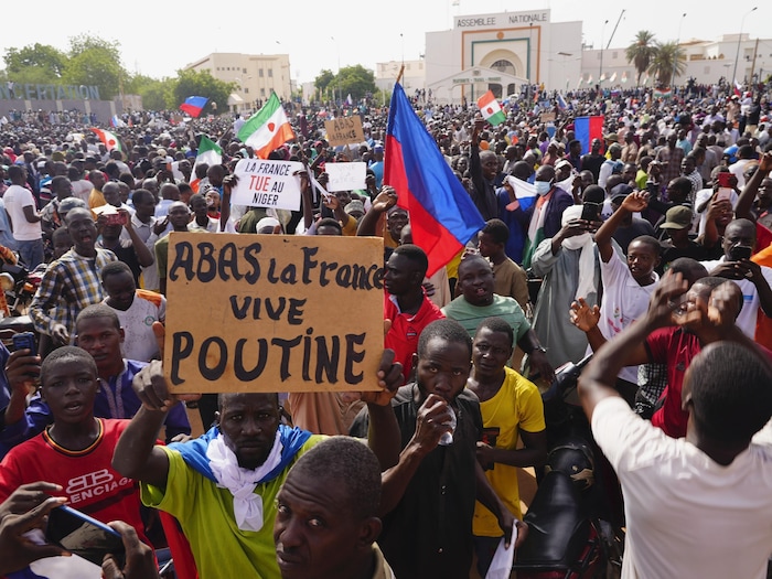 Des gens manifestent avec des drapeaux russes et une pancarte qui porte la mention « À bas la France, vive Poutine ».