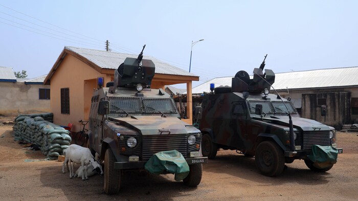 Deux véhicules militaires devant une bâtisse.