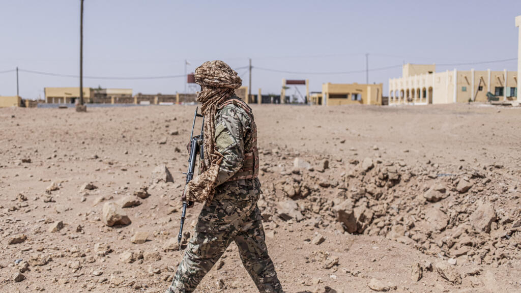 Un militaire inspecte un cratère laissé par un bombardement aérien à Kidal, illustrant les tensions sécuritaires au Mali.